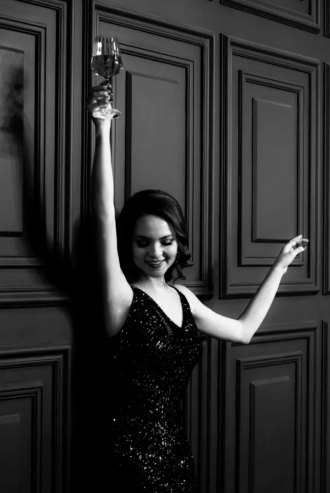 Happy lady in dress with raised hands and wineglass